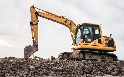 Heavy Equipment RentalsA yellow excavator sitting on the top of soil on a cloudy day.